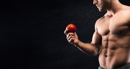 Sporty young man with beautiful torso holding fresh red apple
