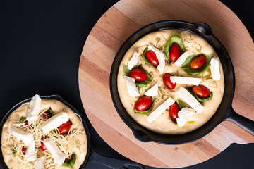 Food concept rising dough for Homemade organic Focaccia in skillet iron pan on black background with copy space