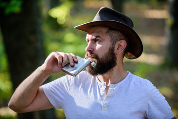 Hipster with beard drink alcohol nature background defocused. Hiking camping. Wanderer concept....