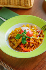 Farfalle pasta with the chicken and tomatoes on a green plate.