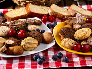 Oatmeal Cookies and sand chocolate cake with blueberries on wooden table in farm style close up. Table setting breakfast for two
