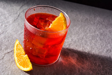 Negroni cocktail with piece of orange on gray stone background