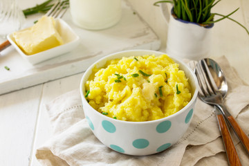 Mashed potatoes in bowl with butter and milk on white wooden rustic table. Free space for your text.