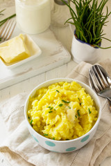 Mashed potatoes in bowl with butter and milkon white wooden rustic table.