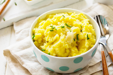 Mashed potatoes in bowl with butter and milkon white wooden rustic table.