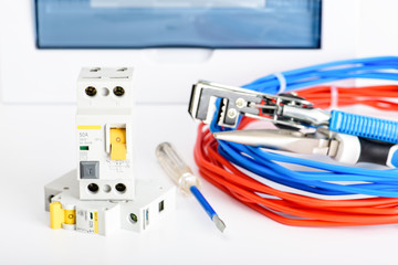 Automatic circuit breakers, distribution box, cable and digital multimeter on a white background. Electrical equipment. Accessories for electrical protection and control