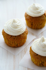 Carrot cupcakes with vanilla frosting. White wooden table, high resolution