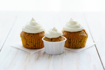 Carrot cupcakes with vanilla frosting. White wooden table, high resolution