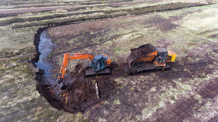 Aerial view of machinery harvesting peat bog during early summer in rural Ireland