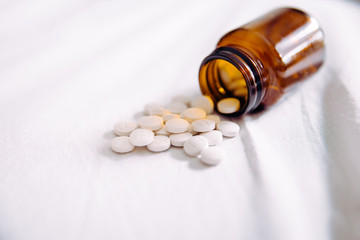 Pills spilling out of pill bottle on white, copy space. Medicine concept