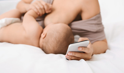 Obraz na płótnie Canvas Millennial mother using smartphone during breastfeeding baby