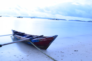 Long exposure shot of the ocean and a pier in a blue time with the old boats defocused. uploaded at Bandar Lampung. Indonesia in May 2019. Traveling concept