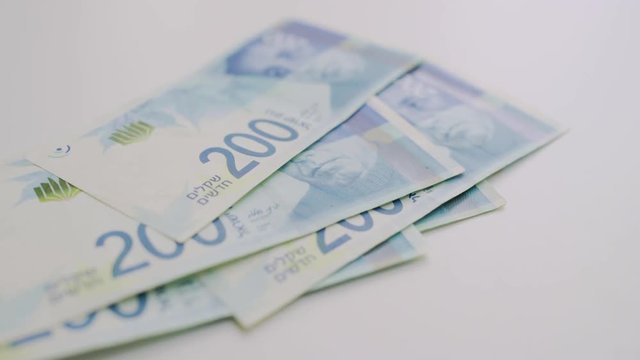 Israeli 200 shekel bills being counted and dropped on table