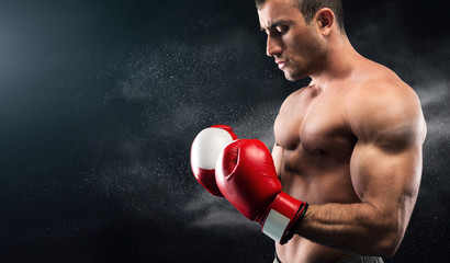 Young boxer looking on his hands in gloves and posing