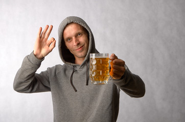 The guy in the hood looks at the mug of cold light beer