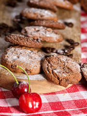 Oatmeal cookies with husk oats and cherry cupcake with powdered sugar on kitchen cutting board gingham checkered cotton fabric on table in village style for picnic. Perfect for breakfast.
