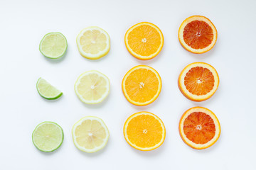 Fototapeta na wymiar Citrus slices pattern on white background from above. Top view of orange, grapefruit, lime and lemon fruit slices on white background. Fruit summer cocktail pattern design