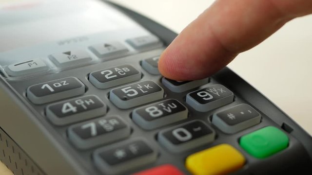 Customer paying with contactless credit card with NFC technology. Credit card reader machine at bar counter. Finger entering PIN code
