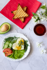 Fried eggs with lettuce, cucumber and tomato slices on a light background