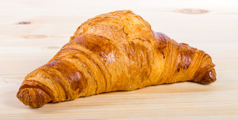 A croissant isolated on a wooden surface