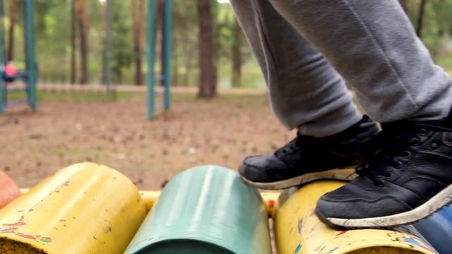 boy in sneakers runs on a treadmill on the playground in the open air