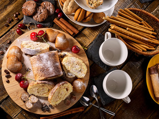 Sand chocolate cookies heart shape and rolled cake with cherry and cinnamon stick on kitchen on wooden table in village style morning sun flare. Freshens usual recipe. Breakfast for loved one.
