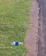 Fototapeta premium A plastic bottle lies discarded on a pavement next to a public street image with copy space