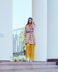 The girl in beautiful and fashionable clothes. Posing at the columns of the theater.