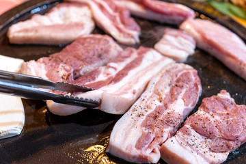 Pan-fried black pork meal in Korea restaurant, fresh delicious korean food cuisine on iron plate with lettuce, close up, copy space, lifestyle
