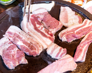 Pan-fried black pork meal in Korea restaurant, fresh delicious korean food cuisine on iron plate with lettuce, close up, copy space, lifestyle