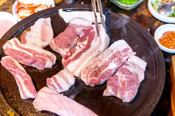 Pan-fried black pork meal in Korea restaurant, fresh delicious korean food cuisine on iron plate with lettuce, close up, copy space, lifestyle