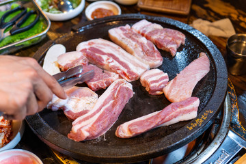 Pan-fried black pork meal in Korea restaurant, fresh delicious korean food cuisine on iron plate with lettuce, close up, copy space, lifestyle
