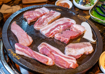 Pan-fried black pork meal in Korea restaurant, fresh delicious korean food cuisine on iron plate with lettuce, close up, copy space, lifestyle