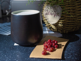 The black glass is filled with hot milk.Sweet red bean paste on brown cardboard.In the background is a basket of green plants in the light。
