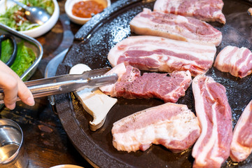 Pan-fried black pork meal in Korea restaurant, fresh delicious korean food cuisine on iron plate with lettuce, close up, copy space, lifestyle