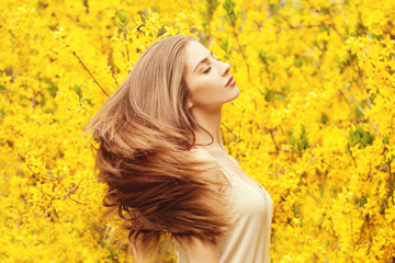 Naklejka premium Romantic woman on yellow flowers background. Pretty girl with blowing hair