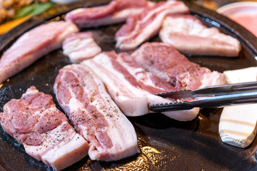 Pan-fried black pork meal in Korea restaurant, fresh delicious korean food cuisine on iron plate with lettuce, close up, copy space, lifestyle