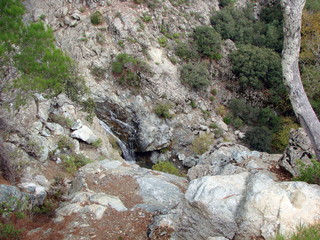Panorama of the rocky surface of the slope of the mountain range, through which stones break through the rapid flow of an underground mountain river.