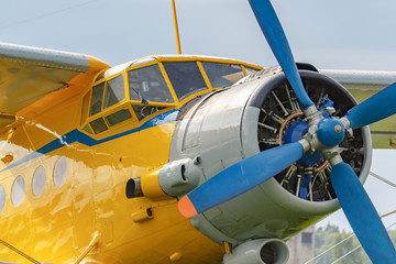 Fototapeta na wymiar Yellow pilots cabin and engine with blue four blade propeller of soviet aircraft biplane Antonov AN-2 closeup