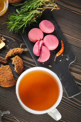 Fresh macaroons with tea on a wooden background