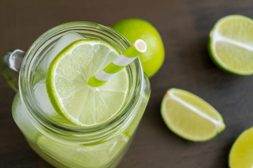 Detox water with lime and ice on a dark background.