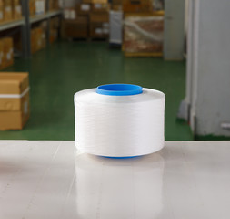 White thread spool in the warehouse of a textile factory. Thread for knitting production.