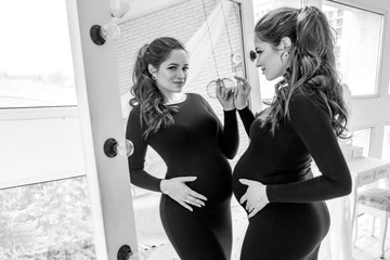 Gorgeous brunette pregnant woman at home in black dress