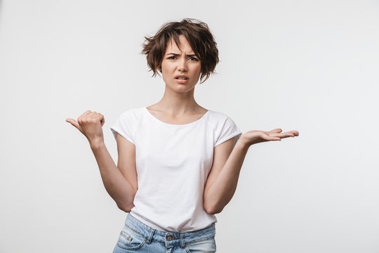 Image of upset woman with short hair in basic t-shirt pointing finger aside at copyspace