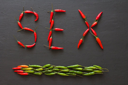 Word Sex Red Hot Chili Peppers On Black Background on Black Table. Swx letter arranged from red chili peppers. Copy space for your text. Flat lay, top view. Words from food and vegetables. Erotica