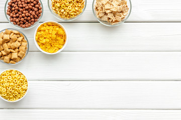 Various corn cereals in bowls on white wooden background top view copyspace