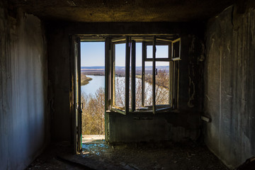 Broken window overlooking the river in an old, abandoned and burned down building after an earthquake