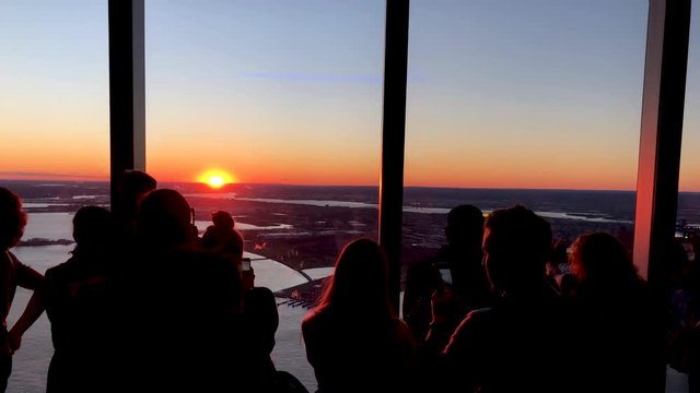 Slow motion of people taking sunset pictures from the top of a city tower