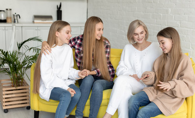 Happy young lesbian couple with two beautiful daughters with long hair, all dressed casual