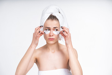 young white girl peels off patches for eyes. Upset. Facial, skin care. Beauty treatments